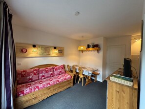 Una habitación acogedora con un sofá de madera, una mesita y un televisor.