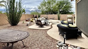 An outdoor patio with seating, a table, and a large plant. - Oro Valley Home For Rent w/ Spa & Views (Oro Valley)
