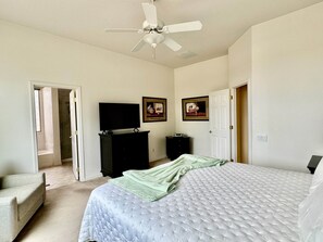 Ein Schlafzimmer mit einem Bett, einem Fernseher, einer Kommode und einem Deckenventilator.