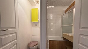 Et badeværelse med toilet, vask og bruseområde.