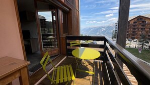 En balkon med trægulv, et gult bord og en gul stol.