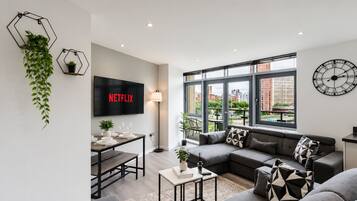 A modern living room with a sofa, coffee table, and a TV displaying 'NETFLIX'.