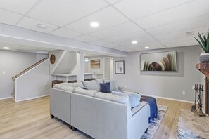 Ein modernes Wohnzimmer mit einem grauen Ecksofa, einer Treppe und einer Küchenzeile.