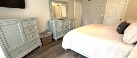 Un dormitorio con una cama, dos cómodas, un ventilador de techo y un espejo.