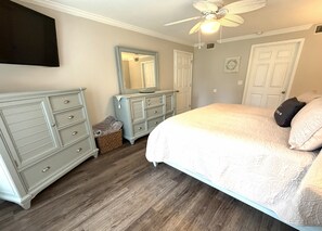 Ein Schlafzimmer mit einem Bett, zwei Kommoden, einem Deckenventilator und einem Spiegel.