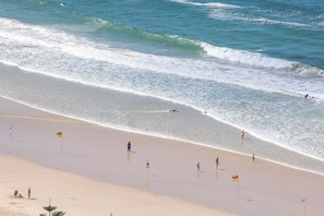 A beach with clear skies, waves, and people. - Luxury Penthouse | Sandbar Burleigh Heads (Gold Coast)