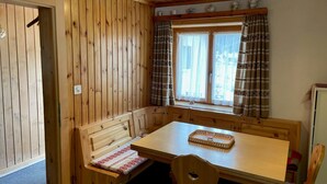 Un intérieur en bois avec un banc, une table et une fenêtre agrémentée de rideaux.