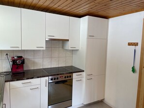 A kitchen with white cabinets, a black countertop, and a stainless steel oven. - Tga Crap Appartement/Fewo, Dusche, WC, 1 Schlafraum 2.5 Zimmerwohnung - 4 Betten by Interhome (Savognin)