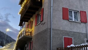 Un bâtiment avec des volets rouges, un balcon décoré de guirlandes lumineuses et une enseigne sur laquelle on peut lire « TGA CRAP ».