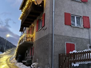 Ein Gebäude mit roten Fensterläden, einem Balkon mit Lichterketten und einem Schild mit der Aufschrift 'TGA CRAP'.
