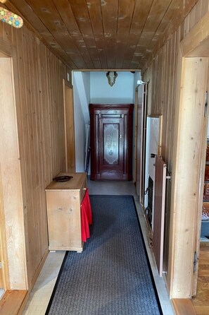 A hallway with wooden walls, a dark carpet, and a door at the end. - Tga Crap Appartement/Fewo, Dusche, WC, 1 Schlafraum 2.5 Zimmerwohnung - 4 Betten by Interhome (Savognin)