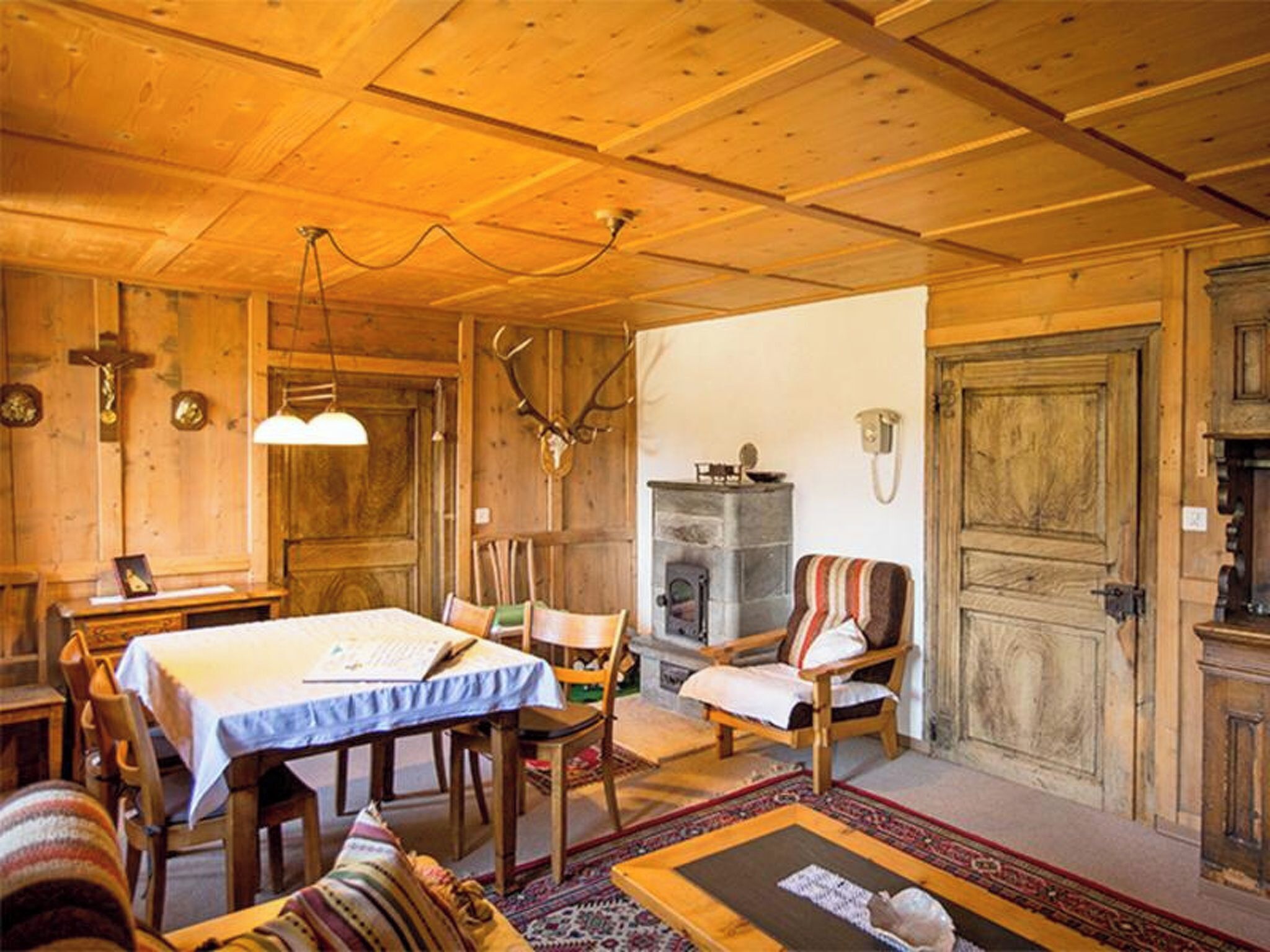 Ein Holzinterieur mit Esstisch, Stühlen, Kamin und einer großen Holztür.