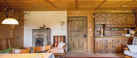 A rustic cabin interior with a dining area, a fireplace, and wooden cabinets.