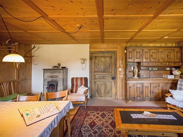 A rustic cabin interior with a dining area, a fireplace, and wooden cabinets.