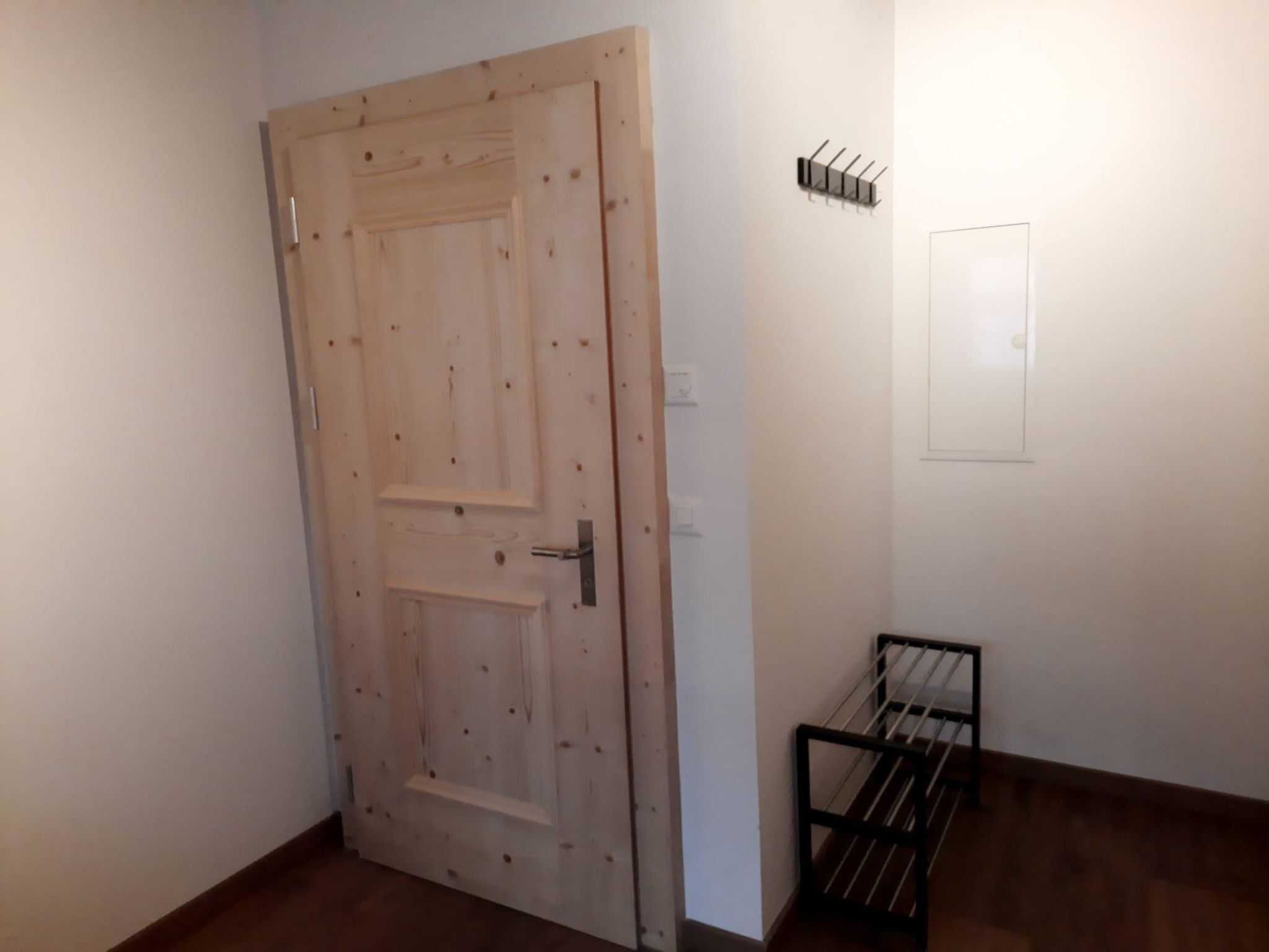Een houten deur met een deurklink en een metalen rek aan de muur.