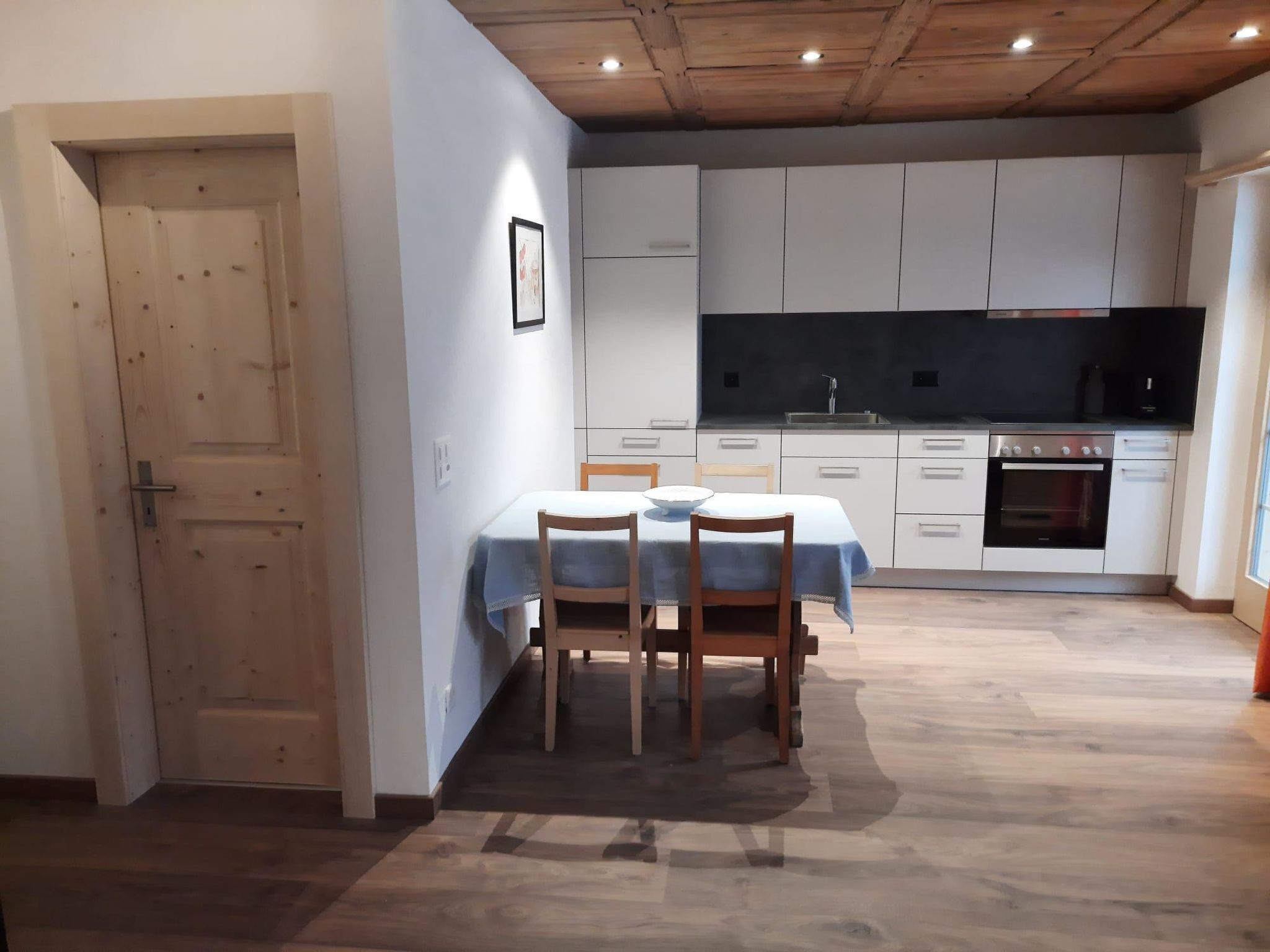 A compact kitchen with white cabinets, a black countertop, and a built-in oven.