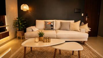 A modern living room with a sofa, two coffee tables, a potted plant, and decorative items.