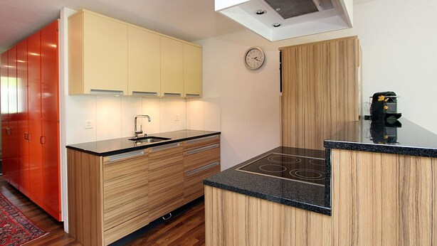 Una cocina moderna con armarios de madera, encimera negra y cocina integrada.