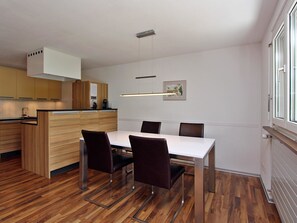 Eine moderne Küche mit Holzschränken, einem weißen Esstisch und Stühlen.