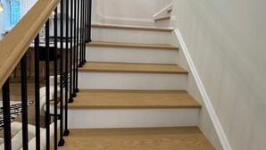 Eine Treppe mit Holzhufen und schwarzen Metallgeländern.