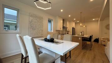 A modern kitchen with white cabinets, a dining area with a white table and chairs, and a wooden floor.