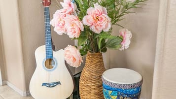 Una guitarra, un jarrón decorativo con flores y un tambor.