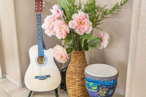 A guitar, a decorative vase with flowers, and a drum.