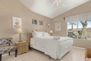 A bedroom with a bed, bedside tables, a chair, and artwork on the walls.
