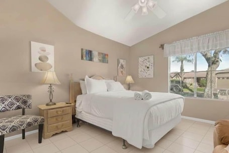 A bedroom with a bed, bedside tables, a chair, and artwork on the walls.