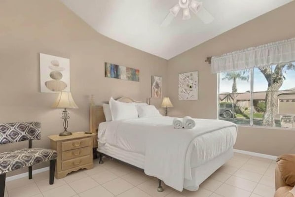 A bedroom with a bed, bedside tables, a chair, and artwork on the walls.