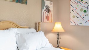 En pænt redt seng med hvide sengetæpper, et træhovedgærde og et sengebord med en lampe.