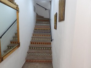 Eine Treppe mit aufwendiger Geländerkonstruktion und gemusterten Fliesen.