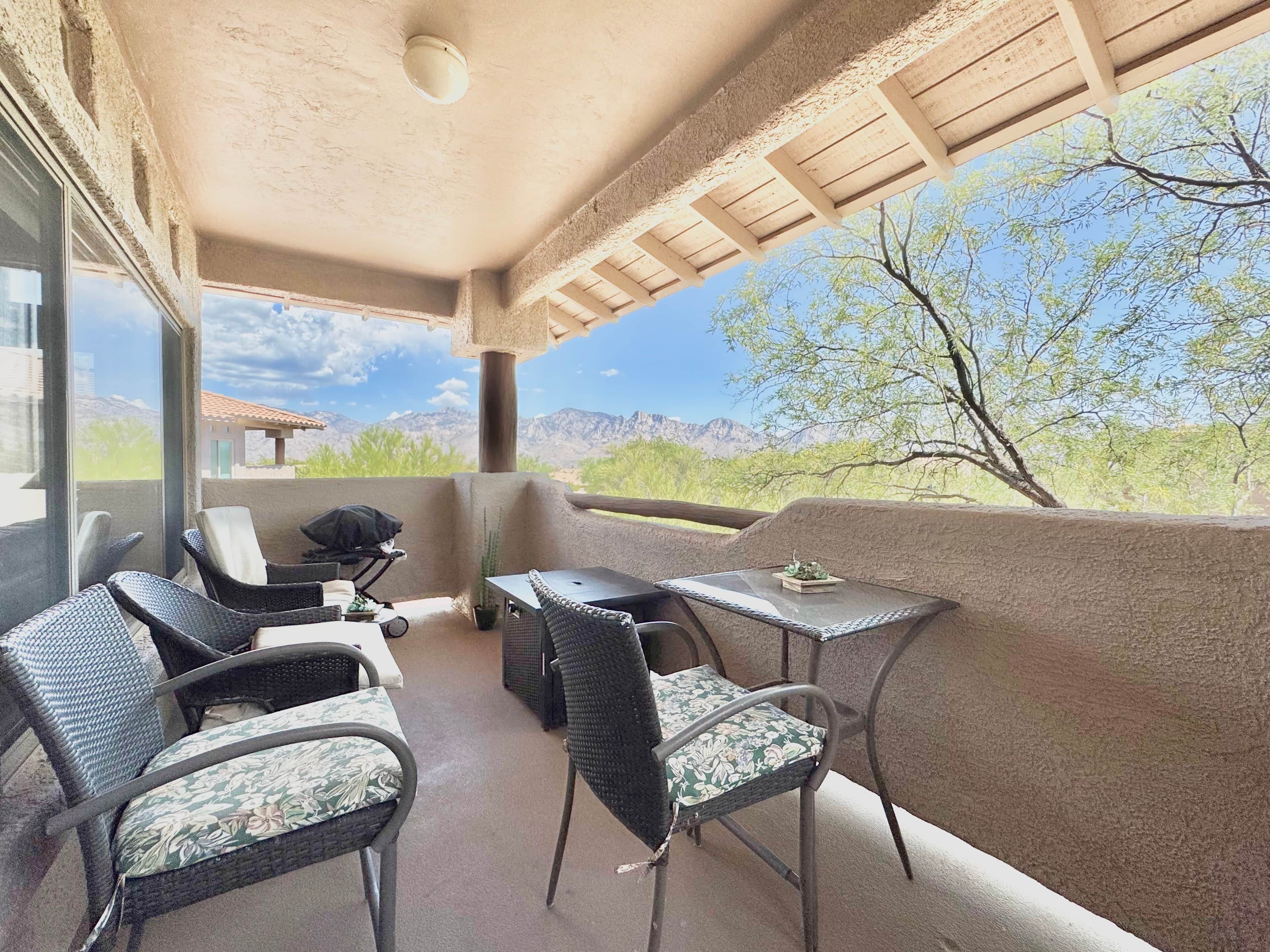 An outdoor patio with wicker furniture, a table, and a view of a mountainous landscape.