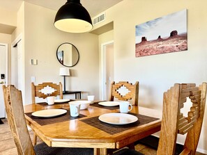 Un coin repas avec une table en bois, quatre chaises et un tableau accroché au mur.