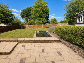 A backyard with a swimming pool, a wooden fence, and a well-maintained lawn. - Vivian - Luxury 2 bed House (Watford)