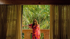A room with a bed, a chair, and a view of greenery through a window. - Waves Sunzal (Tamanique)