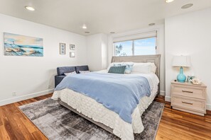 Ein Schlafzimmer mit einem Bett, Nachttischen, einem Fenster und einem Bild an der Wand.