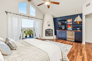 Ein Schlafzimmer mit einem großen Bett, einem Deckenventilator und Blick ins Freie.