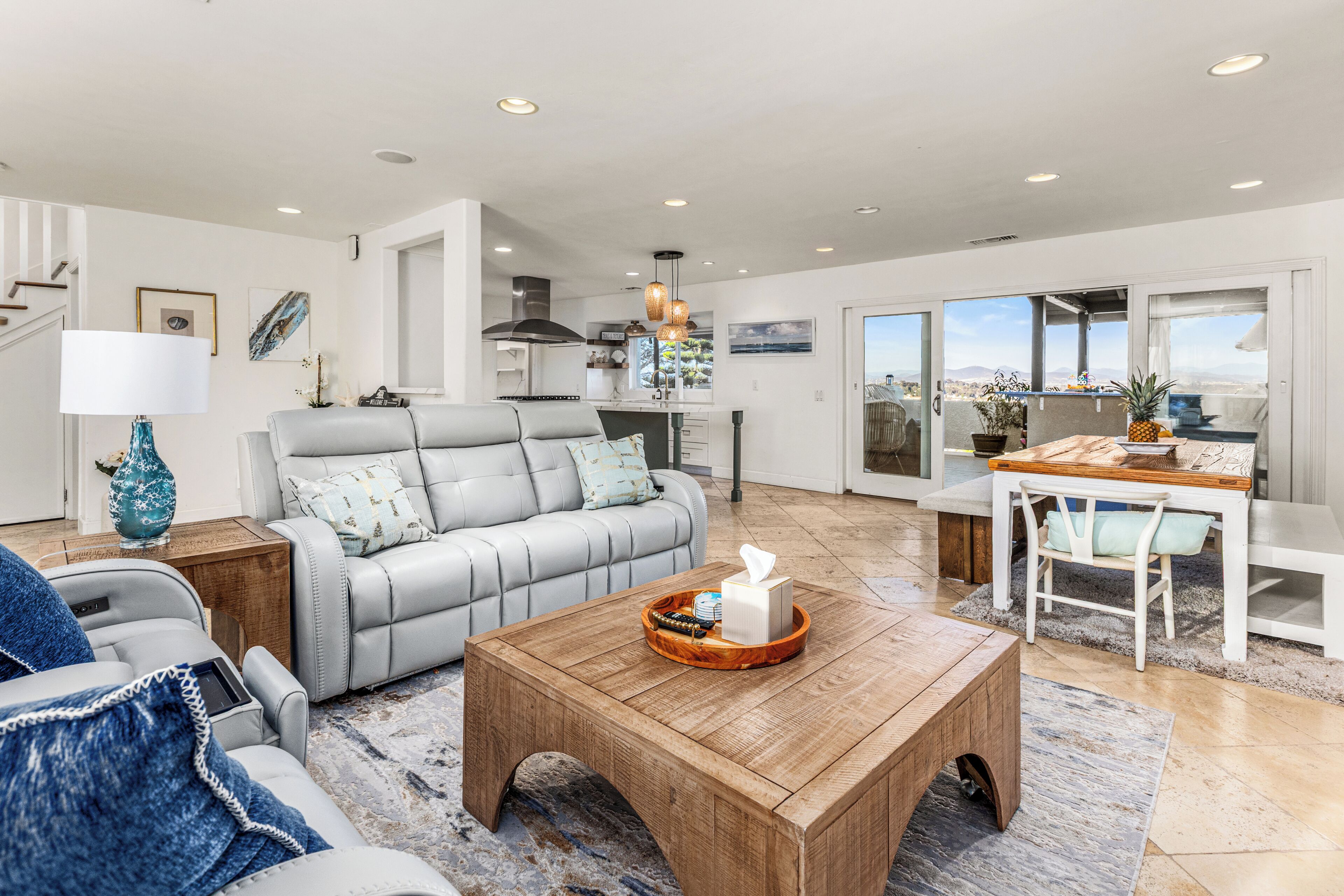 A spacious living area with a grey sofa, wooden coffee table, and a dining table with chairs.