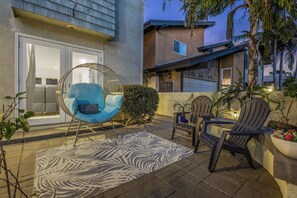 A patio with outdoor seating, a patterned rug, and a house with a garage. - Del Mar Coastal Luxury: Minutes to Beach & Trails (Del Mar)