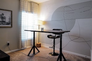 A room with a desk, a chair, a lamp, and a large abstract wall painting. - Enjoy this Home in Wesley Chapel.  Designed for Relaxation/Comfort/Remote Work (Wesley Chapel)