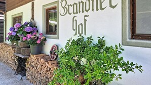 Um edifício com o nome 'Brandnegg' pintado na parede, vigas de madeira no topo e uma janela com moldura de madeira.