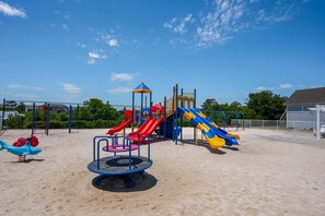 A playground with multiple slides and a merry-go-round. - Ballast Point Villa 1411: Soundfront, Pirate's Cove Community Amenities, Water Views (Manteo)