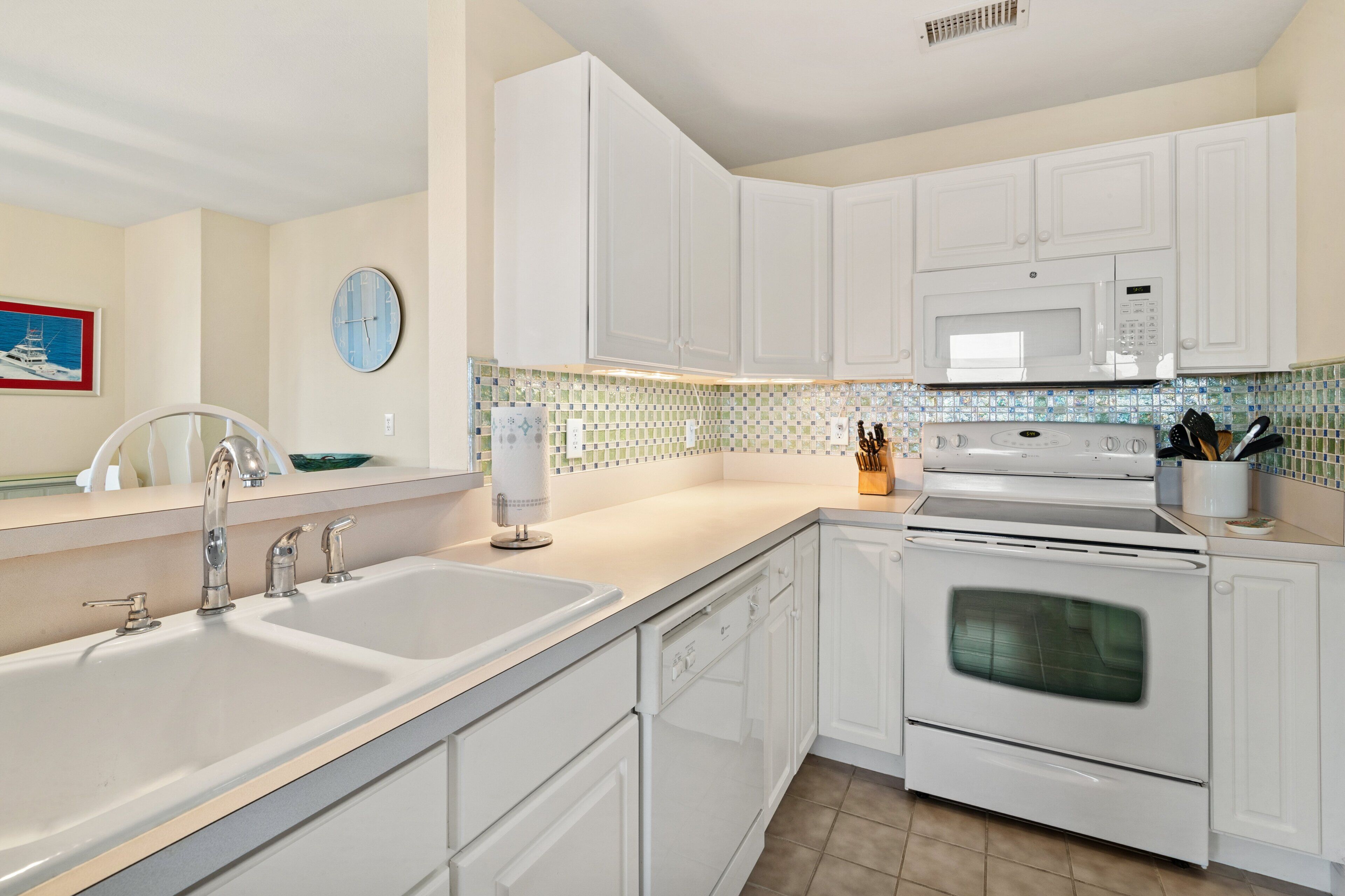 A kitchen with white cabinets, a sink, a microwave, and an oven.