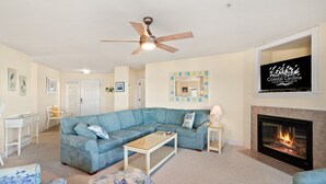 Ein Wohnzimmer mit Ecksofa, Couchtisch, Kamin und Deckenventilator.