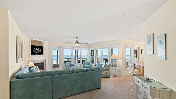 Ein geräumiges Wohnzimmer mit einem großen, grünen Sofa, einem Kamin und Blick auf das Wasser.