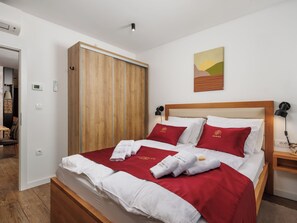 A hotel room with a bed, a wooden wardrobe, a painting on the wall, and a bedside table with a lamp. - Valera Vita Forest by Interhome (Skrad)