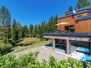 A modern house with a stone deck, outdoor seating, and a swimming pool. - Valera Vita Forest by Interhome (Skrad)