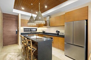 A modern kitchen with a central island, wooden cabinets, a stainless steel refrigerator, and pendant lighting. - 5 stars Luxury Retreat  Rooftop Pool Whirlpool tub (tulum)