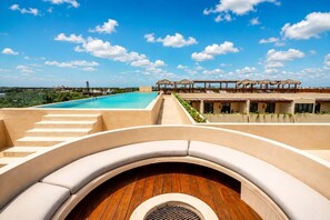 A rooftop pool area with a clear view of the ocean, a wooden deck, and a series of steps leading to a covered seating area. - 5 stars Luxury Retreat  Rooftop Pool Whirlpool tub (tulum)